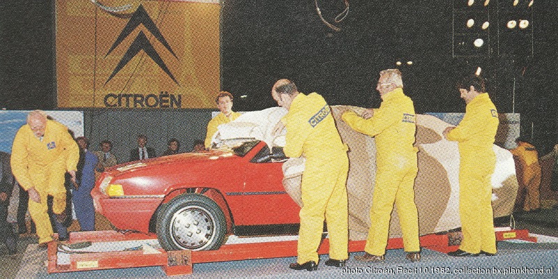 Mannen in pakken in de Citroen kleuren pakken de BX uit, een rode BX 16 TRS